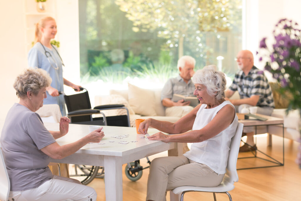 Senior women enjoying time while sitting at table and puzzling in a senior assisted living facility.