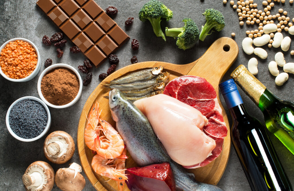 A group of food items including chocolate, broccoli, beans, cooking oil, raw fish, mushrooms and spices. 