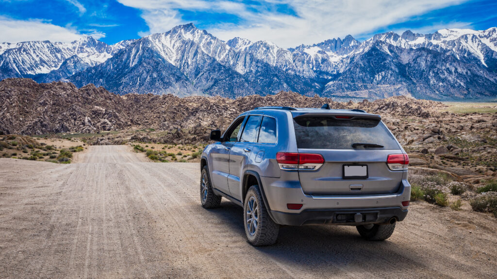 SUV driving on a dirt road towards mountains