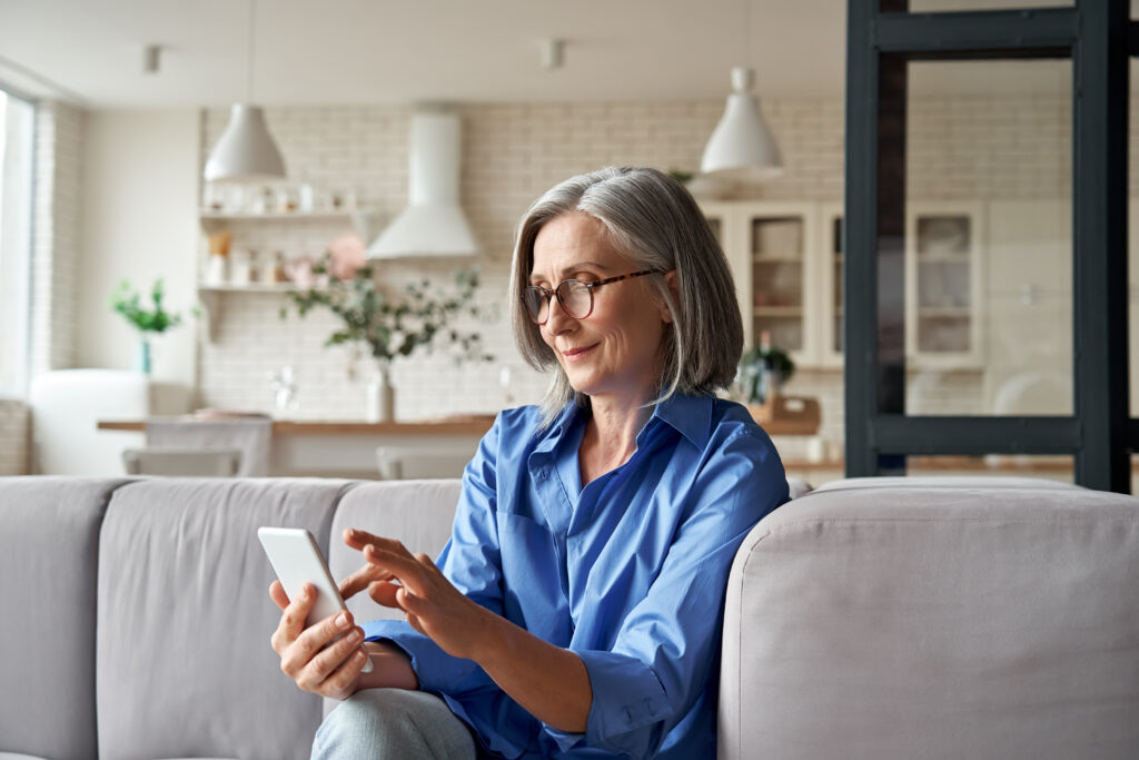 Older woman using smart phone in her living room.