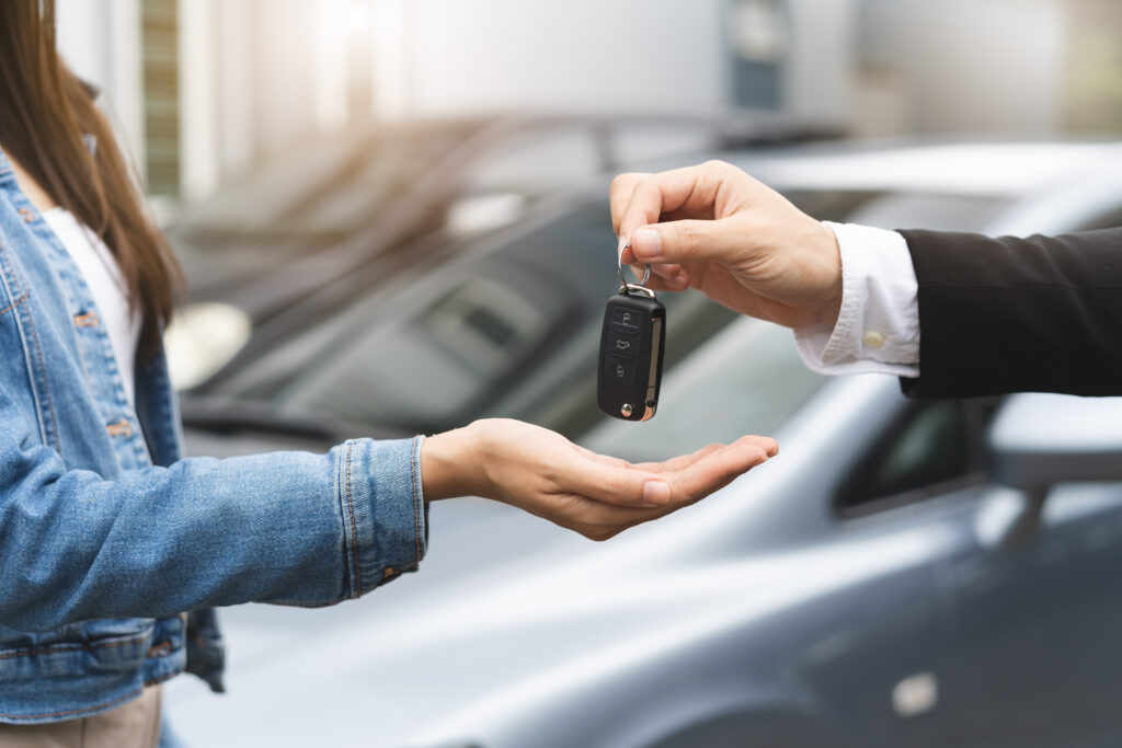 Close up hands of rental auto agent giving car remote key to client.