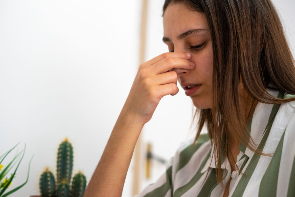 Woman holding her nose in pain. 