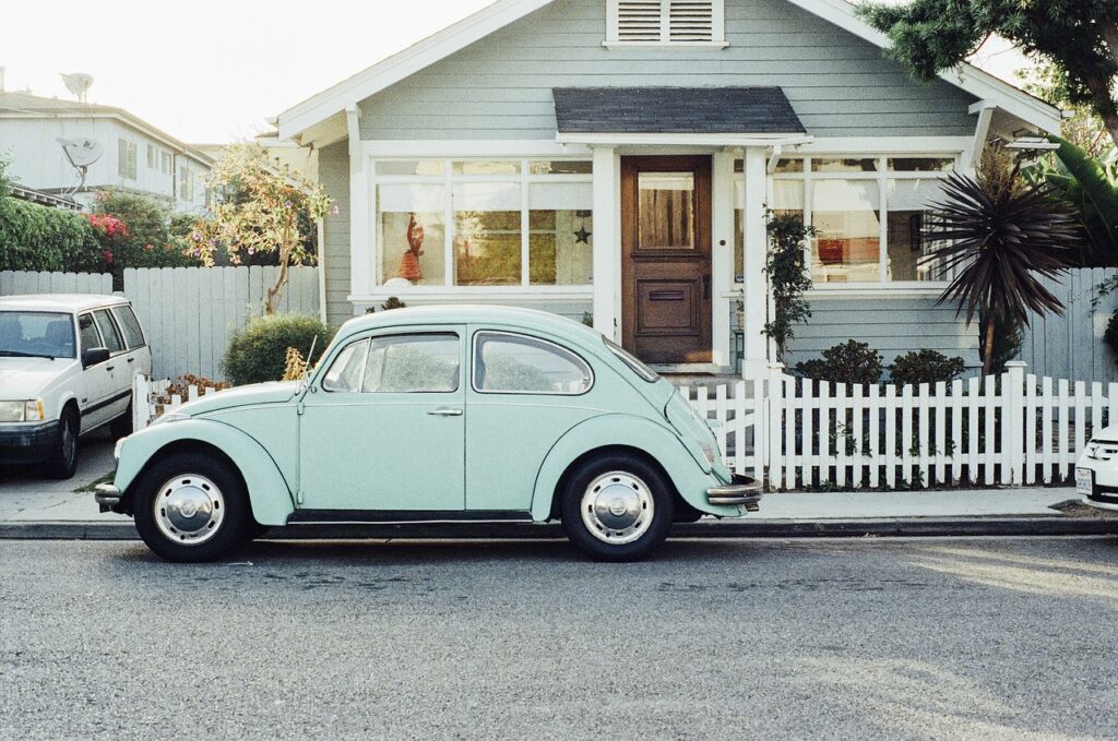 vintage wv beetle parked in front of a home on the street